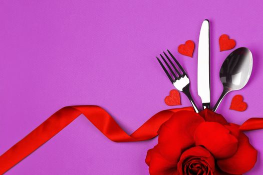 Love, romance, Valentine's day concept - festive table setting cutlery, rose flower and decorative hearts on purple background