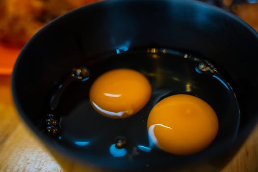 The Yellow egg white and yolk baking ingredient in a black bowl