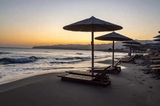 Sunbeds and umbrellas at sunrise on Stalis beach in northern Crete