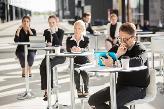 Lot of business people sitting in cafe of modern office building
