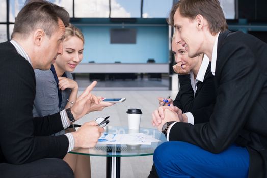 Portrait of happy business people talking at break in cafe sitting together at the table