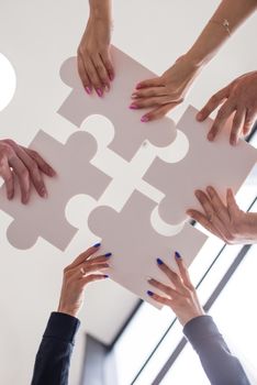Hands of business people holding white puzzle