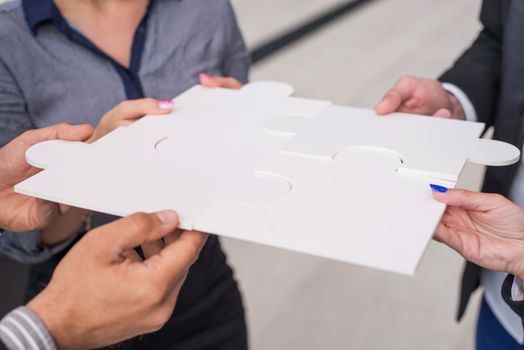 Hands of business people holding white puzzle