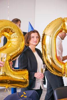 Business people celebrating 2020 New Year at office party, mature woman thinking about future