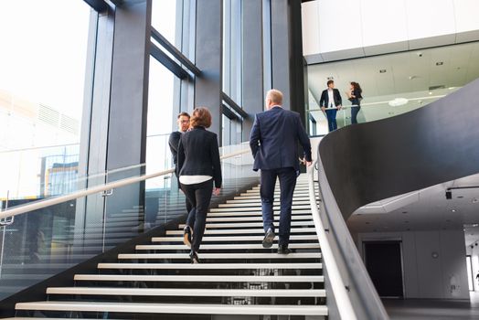 Modern business people walking on stairs in glass hall of office building