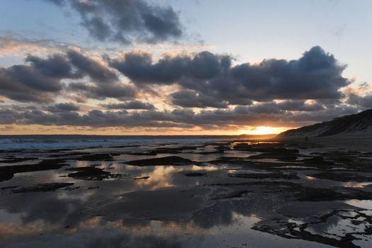 Dusk sunset horizon over low tide beach rock pools, Mossel Bay, South Africa