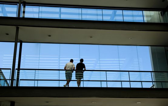 Silhouette view of two young men in a modern office building interior with panoramic windows.