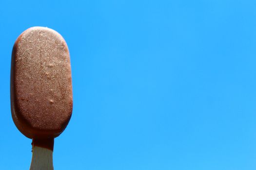 The picture shows a ice cream on a stick and the blue sky.