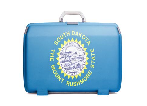 Used plastic suitcase with stains and scratches, printed with flag, South Dakota