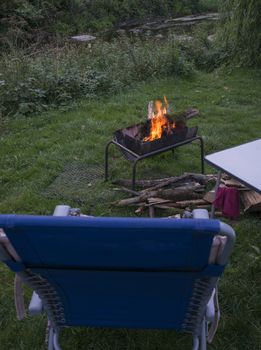 deckchair on a camp with a campfire in a fire pit at the small river