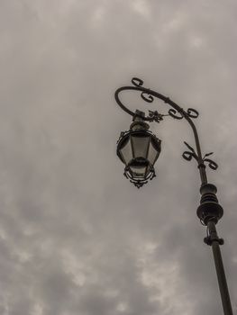 A retro lampost at a dark sky with clouds.