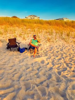 Man is sitting on a beach chair on the beach and enjoys the sun