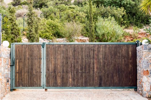 Elegant wooden portico between two stone walls with trees in the background