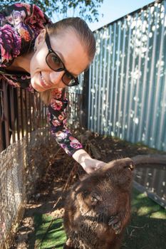 Young woman caress the beaver in petting zoo