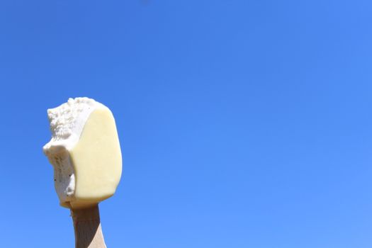 The picture shows an ice cream on a stick and the blue sky.