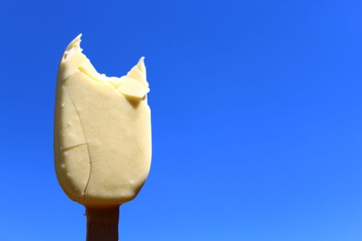 The picture shows an ice cream on a stick and the blue sky.