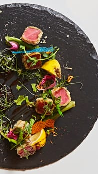 Close up of rare seared Ahi tuna slices with fresh vegetable salad on a plate. Shallow dof