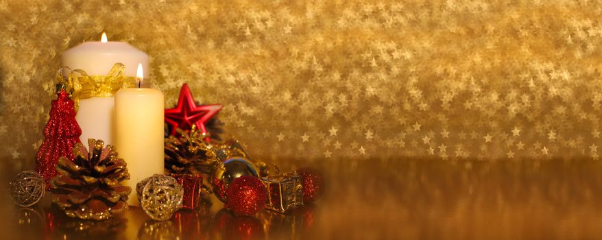Christmas decoration of burning candle and decor over golden star bokeh background