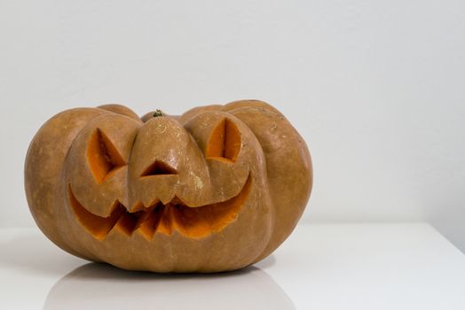 orange halloween pumpkin with carving, crushed and collapsible typology, on a background in nature or white