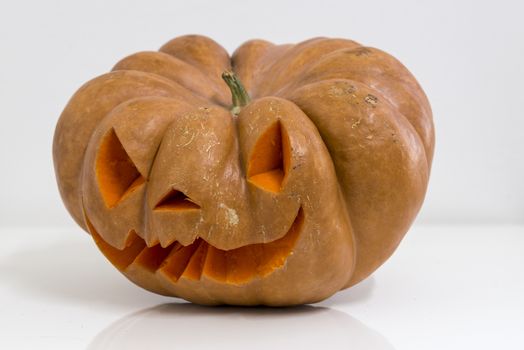 orange halloween pumpkin with carving, crushed and collapsible typology, on a background in nature or white