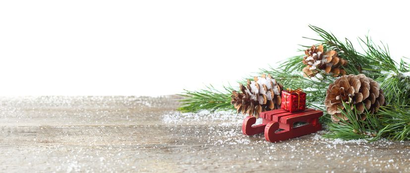 Christmas card. Pine cone and green branch on wooden table with snow, copy space for text, isolated on white background