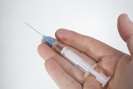 Medical syringe in a male hand on a white background