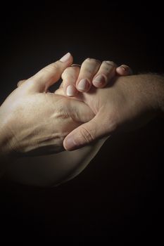 Female hands hold a man's hand on a black background