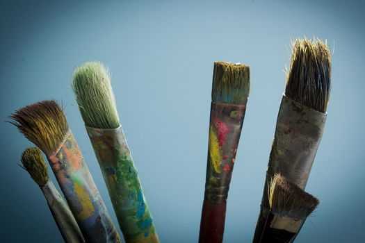 Artist's brushes in paint on a blue background