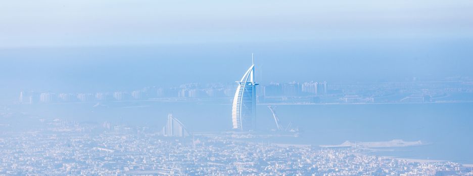 Skyline of Dubai beachfront with Burj Al Arab hotel on Jumeirah beach seen from Burj Khalifa viewpoint. Modern architecture, luxury beach resort, summer vacation and tourism concept.