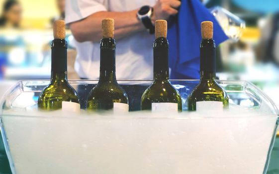 Catering bartender Italian fine wine bottles in winetasting session and a sommelier waiter serving wine to people and clean glasses in the background