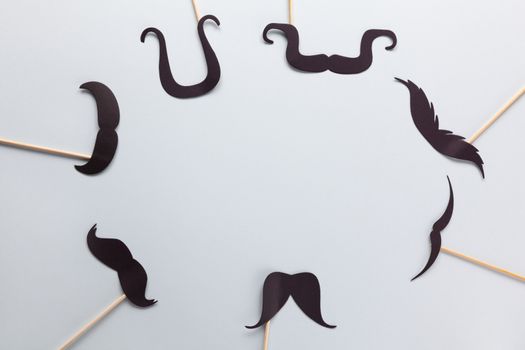 Accessories in form of black moustache on sticks on grey background with place for text. Concept movember, men's health, prostate cancer awareness month, charity, Father's Day. Horizontal. Flat lay.
