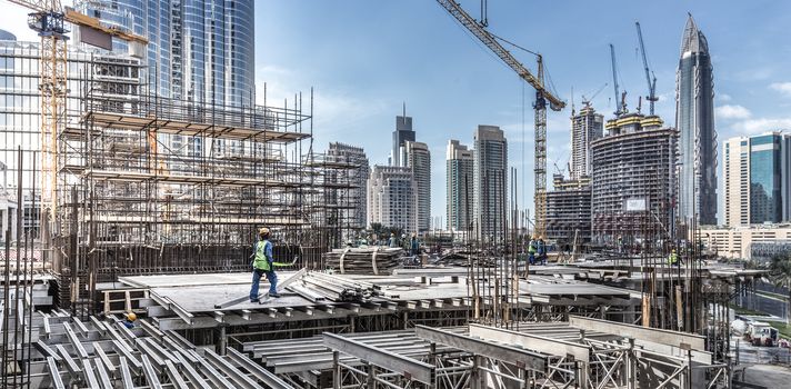 Laborers working on modern constraction site works in Dubai. Fast urban development consept.