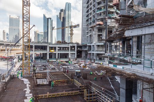 Laborers working on modern constraction site works in Dubai. Fast urban development consept.