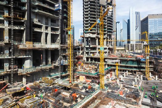 Laborers working on modern constraction site works in Dubai. Fast urban development consept.