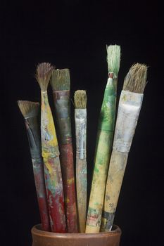 Artist's brushes in paint on a black background