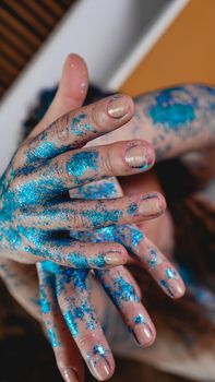 Blue glitter on woman hands. Smooth movements of the hands. Femininity and beauty