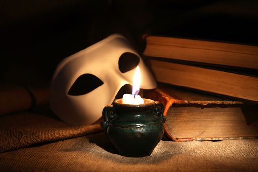 Vintage still life with candle near mask and books