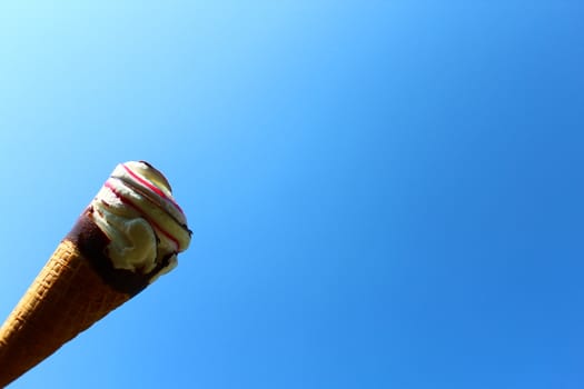 The picture shows an ice cream cone in front of the blue sky.