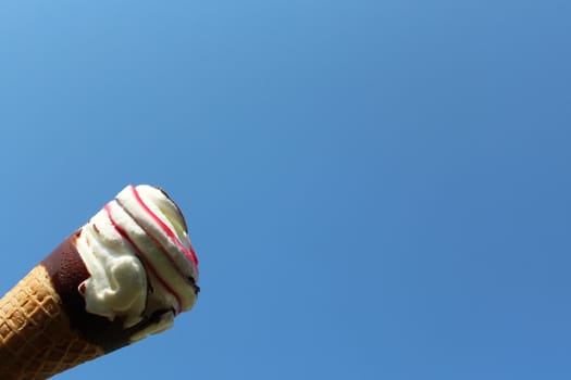 The picture shows an ice cream cone in front of the blue sky.