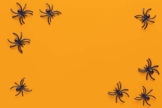 Halloween holiday flat lay. Black spiders on orange background with copy space. Minimal style. Horizontal. Trick-or-treat concept.