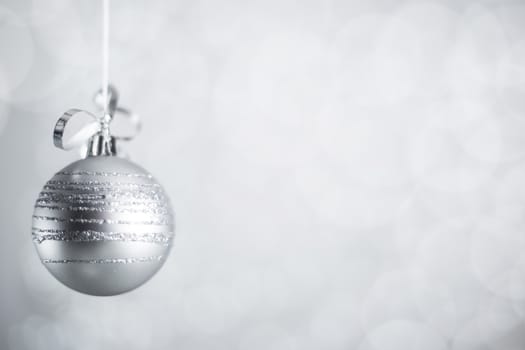 Silver Christmas new year ball with curly streamer ribbon bow over glittering bokeh lights background with copy space for text