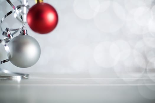 Silver and red Christmas new year balls with curly streamer ribbon bow over glittering bokeh lights background with copy space for text