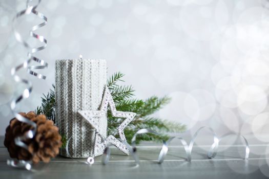 Silver Christmas new year candle with curly streamer ribbon bow decoration over glittering bokeh lights background with copy space for text