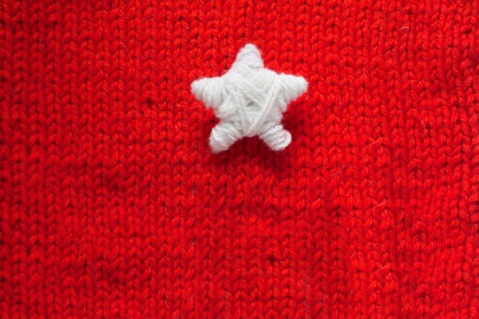 Handmade Christmas Star on red knitted woolen background with copy space for text