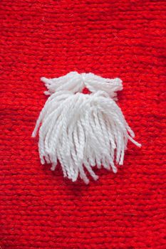 Santa Claus beard on red knitted woolen background with copy space for text Christmas concept