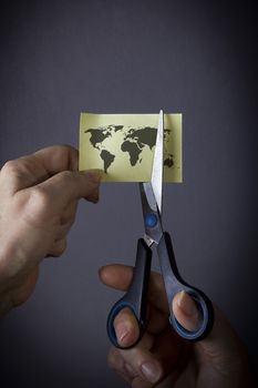 Hand with scissors cuts the world map