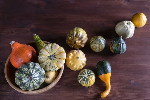 Some small pumpkins on a wooden table in the autumn with some leaves