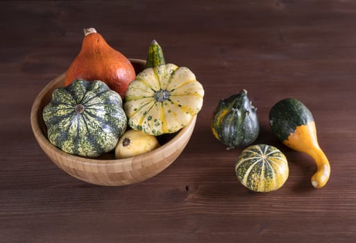 Some small pumpkins on a wooden table in the autumn with some leaves