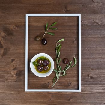 Olive oil with some olives into the frame