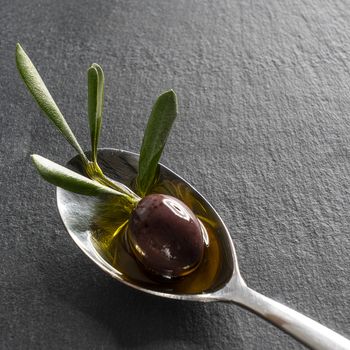 A black olive in the spoon with a black sytone